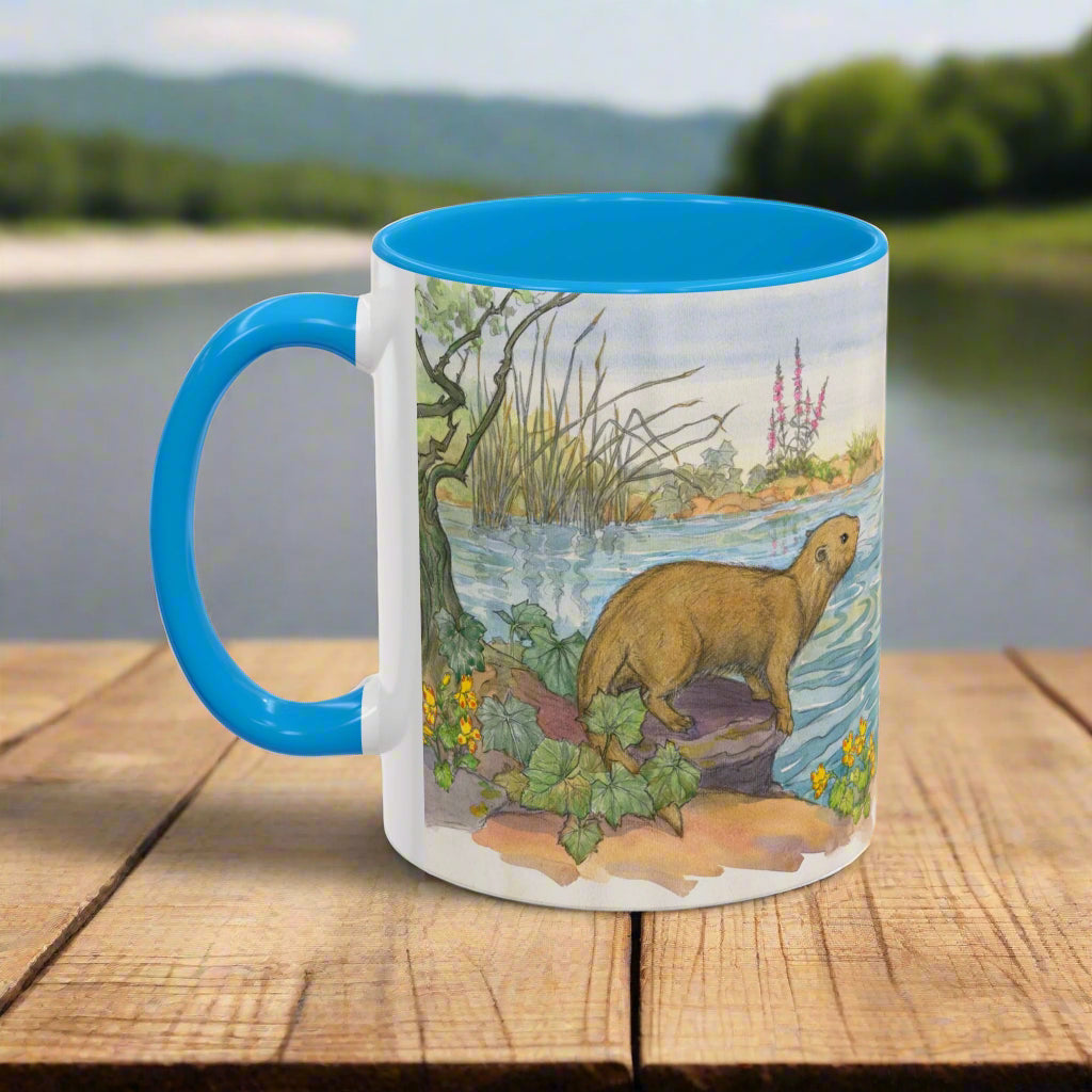 Mug with a blue handle featuring a nature scene with an otter.