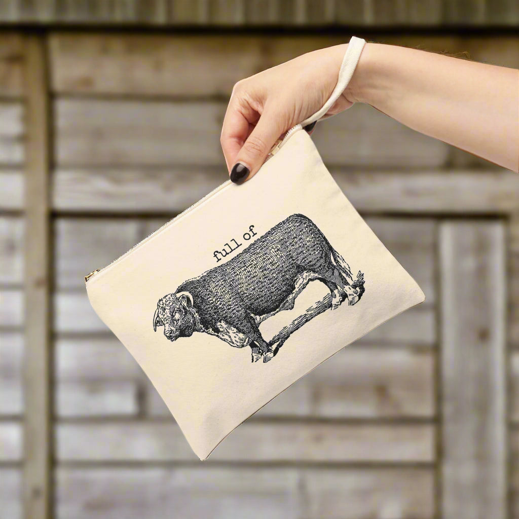 Beige pouch with black bull illustration and 'full of' text held by a hand on a white background