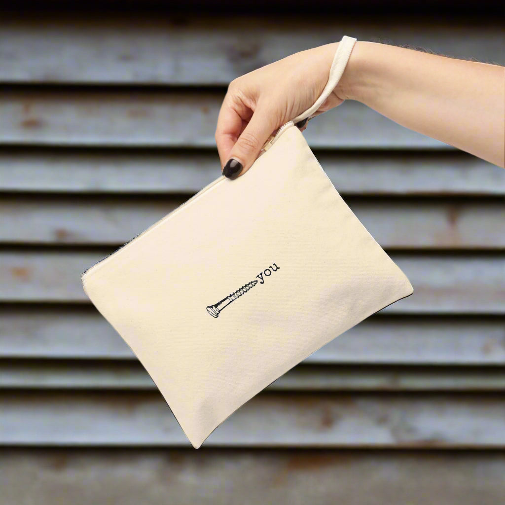 Beige pouch with 'screw you' embroidery held by a hand on a white background