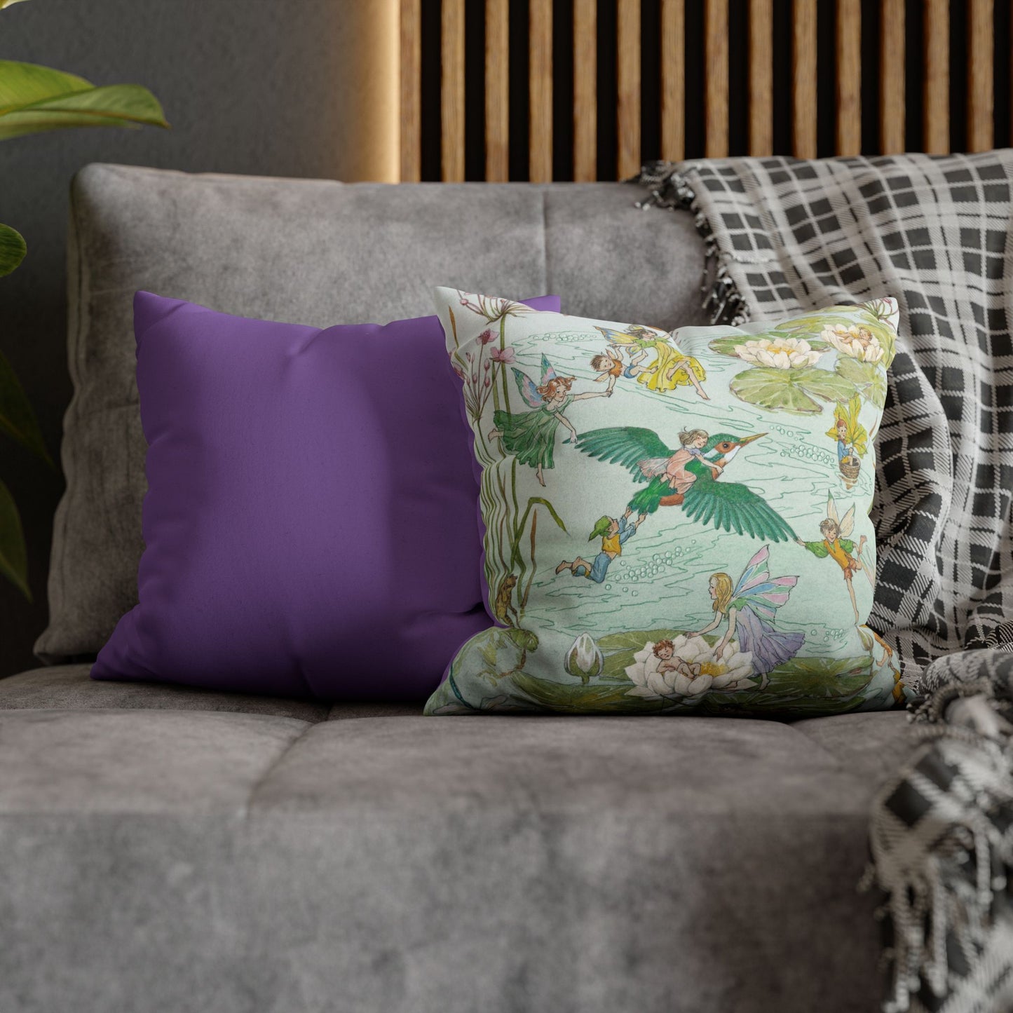 Decorative pillows on a sofa with a fairy design and a purple pillow.